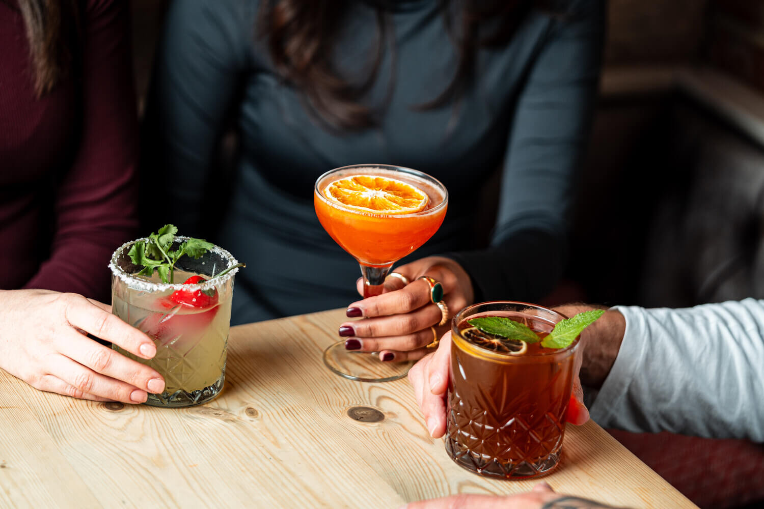 Three different cocktails on a pub table